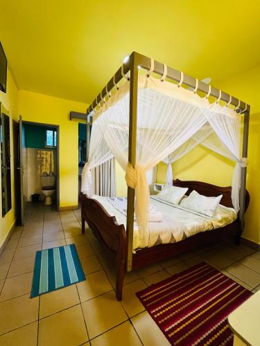 a bedroom with a canopy bed in a yellow room at Hôtel - Appartement meublé " LES FLOTS BLEU " in Antananarivo