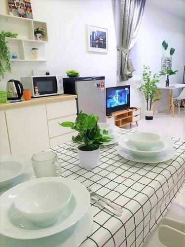 a kitchen with a table with white dishes on it at FlexiHome Studio Newly Renovate - 1 Queen 2 Single in Petaling Jaya