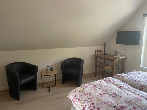 1 dormitorio con 2 sillas, 1 cama y escritorio en Velogement 't Moltje, en Heuvelland