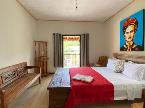 ein Schlafzimmer mit einem großen Bett mit einer roten Decke in der Unterkunft Pousada Artes Evano in Bichinho