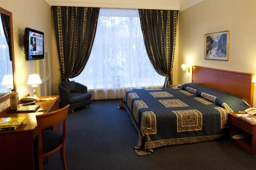 a hotel room with a bed and a desk and a window at Grand Hotel Ukraine in Dnipro