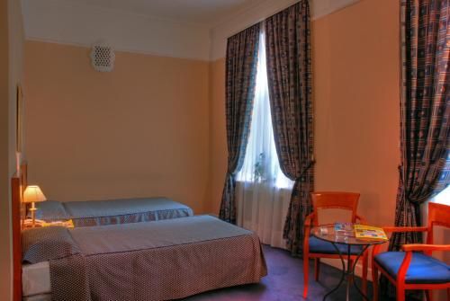 a bedroom with a bed and a table and a window at Grand Hotel Ukraine in Dnipro