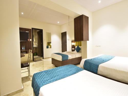 a hotel room with two beds and a desk at Hotel Candor Amigo Airoli Mind Space in Navi Mumbai