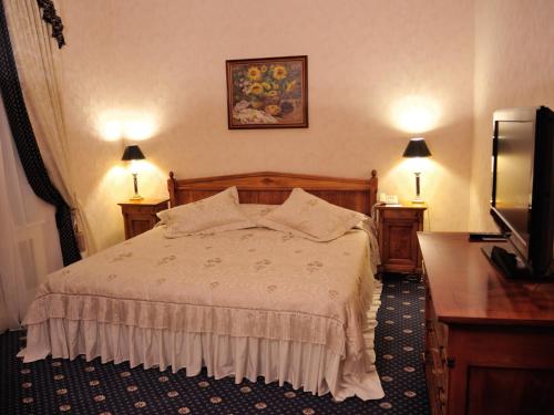 a bedroom with a bed and two lamps and a television at Grand Hotel Ukraine in Dnipro
