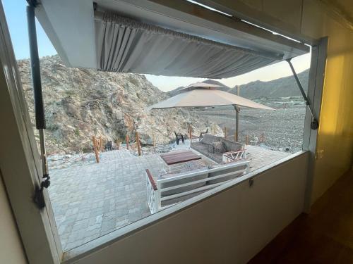 a window with a view of a beach with an umbrella at Al shalal caravan in Fujairah