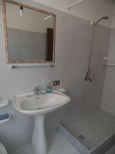 ein weißes Badezimmer mit einem Waschbecken und einem Spiegel in der Unterkunft Casa MoDerna 25SX in Castellammare del Golfo