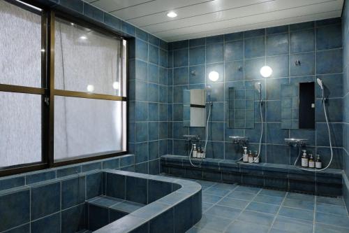 un baño con dos urinarios y una bañera. en DENIM HOSTEL float, en Kurashiki