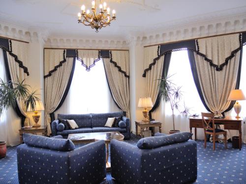a living room with two blue chairs and a couch at Grand Hotel Ukraine in Dnipro