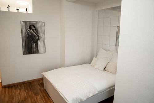 Un pequeño dormitorio con una cama blanca con una pintura en la pared en Ferienwohnung in der Nähe von Köln en Frechen