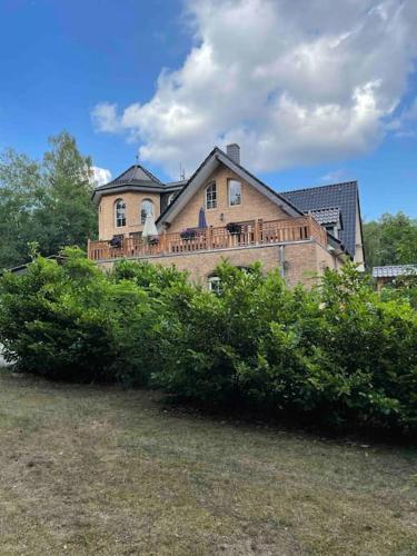 ein großes Haus mit Büschen davor in der Unterkunft Seeblick zwei im Waldschlößchen in Wendisch Rietz