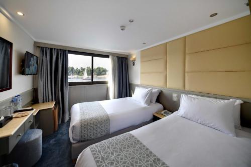 a hotel room with two beds and a window at Nile Treasure Cruise - 4 or 7 Nights From Luxor each Saturday and 3 or 7 Nights From Aswan each Wednesday in Luxor