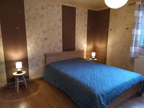 1 dormitorio con 1 cama azul y 2 lámparas en Appartement dans un chalet de montagne, en Guillestre