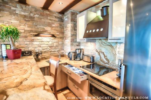 une grande cuisine avec un mur en pierre dans l'établissement Location front de mer de Thierry Bourgait, à Banyuls-sur-Mer