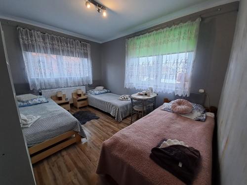 a bedroom with two beds and a table and windows at Pokoje Gościnne u Grażynki in Nowy Sącz