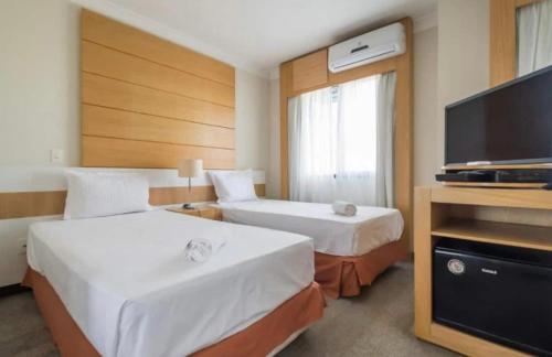 um quarto de hotel com duas camas e uma televisão de ecrã plano em Suíte com vista para o aeroporto de Congonhas. em São Paulo