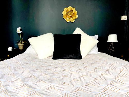 a bed with a black pillow and white pillows at Appartement de standing à Vallorbe in Vallorbe