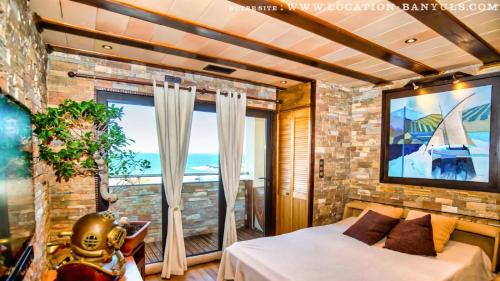 a bedroom with a bed and a large window at Location de charme de Thierry BOURGAIT in Banyuls-sur-Mer