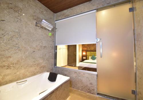 a bathroom with a tub and a mirror and a bed at Hotel Candor Amigo in Navi Mumbai