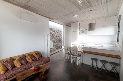 Una sala de estar con un sofá y una cocina. en CASA DA PITANGA, en Jardim do Mar
