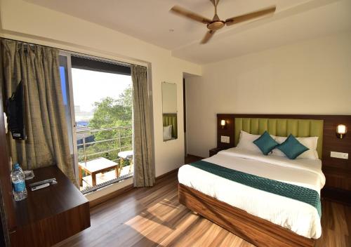 a bedroom with a bed and a large window at Hotel Candor Amigo in Navi Mumbai