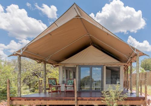 a tent with a table and chairs on a deck at Emhosheni River Lodge in Balule Game Reserve