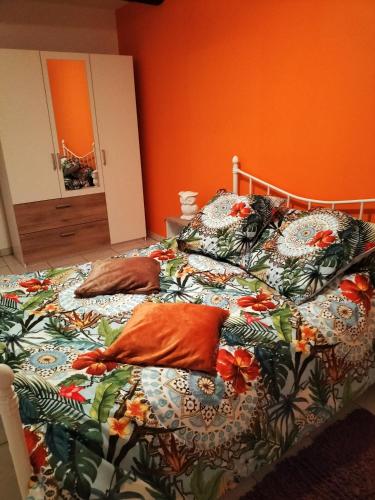a bedroom with two beds with pillows and an orange wall at GITE LE MONTENEY in Pont-Audemer