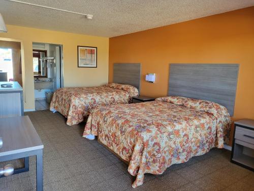 2 camas en una habitación de hotel con paredes de color naranja en Royal Inn en Port Arthur
