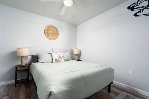 a bedroom with a white bed with a clock on the wall at Cacti - Cactyou - Cactus in San Antonio