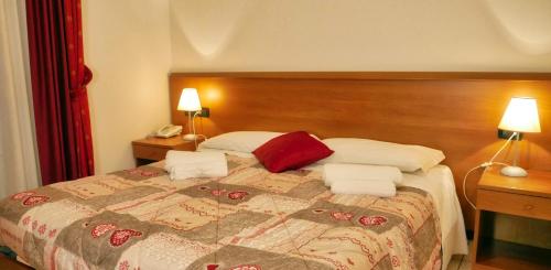 a bedroom with a large bed with two lamps and two towels at hotel Vajont in Vaiont