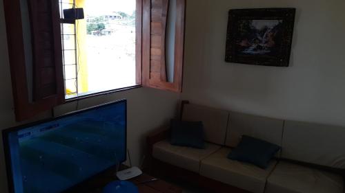 sala de estar con TV de pantalla plana y sofá en Casa clima de montanha, en Gravatá