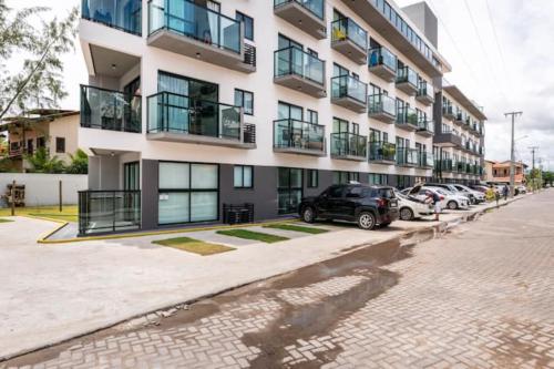 um grande edifício de apartamentos com carros estacionados em frente em Maracaipe, um paraíso para você - Maraca Beach Residence II - ap 111 em Ipojuca