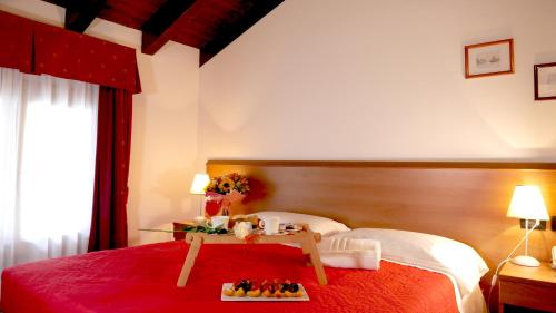 una camera con un letto con una coperta rossa e un tavolo di hotel Vajont a Vaiont