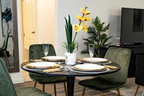 a dining room table with plates and glasses and yellow flowers at Lavishly Decorated 3-Bedroom Home Near Samsung-Taylor with King-Sized Bed in Hutto