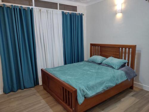 a bedroom with a bed with blue sheets and blue curtains at Stand alone gateway in Kampala