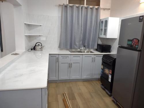 a kitchen with white counter tops and a refrigerator at Stand alone gateway in Kampala
