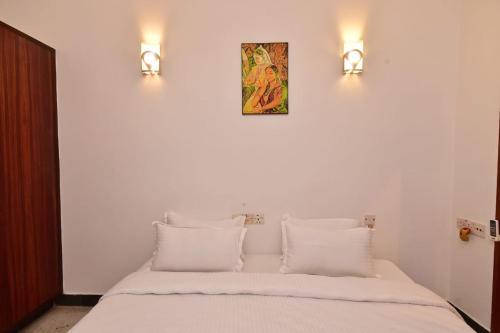 un letto con cuscini bianchi e 2 luci sul muro di Villa Felicia a Pondicherry