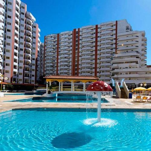 a pool with a red umbrella in front of some buildings at T1- Praia da Rocha com piscina -segunda linha in Portimão