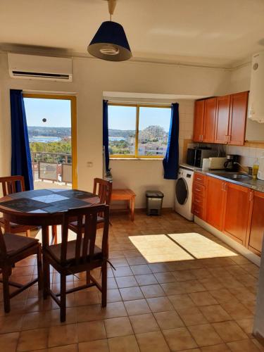 a kitchen with a table and chairs and two windows at T1- Praia da Rocha com piscina -segunda linha in Portimão