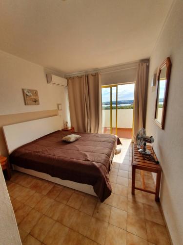 a bedroom with a bed and a window and a table at T1- Praia da Rocha com piscina -segunda linha in Portimão