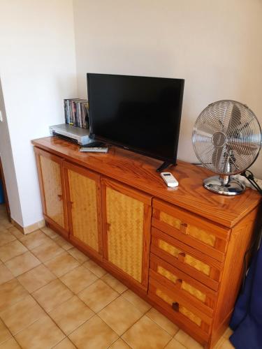 a television on top of a wooden dresser with a fan at T1- Praia da Rocha com piscina -segunda linha in Portimão
