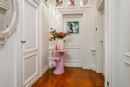 a pink table in a hallway with a vase of flowers at Museum Garden View Apartment Antwerp South in Antwerp