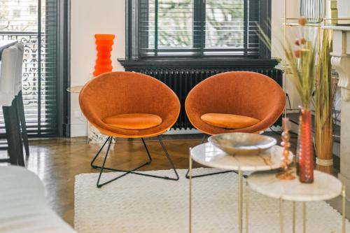 two orange chairs and a table in front of a fireplace at Museum Garden View Apartment Antwerp South in Antwerp