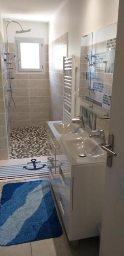 uma casa de banho com um lavatório branco e um tapete azul em Chez Reinette em Capendu
