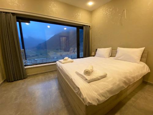 a bedroom with a bed with towels on it with a window at Runaway House - Qalacıq in Gabala