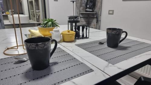 duas chávenas pretas em cima de uma mesa em okeyloft Coyhaique 1 em Coihaique