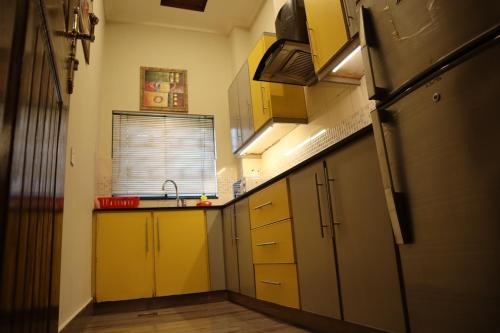 a small kitchen with yellow cabinets and a sink at Hayyat Luxury Hotel Apartments in Lahore