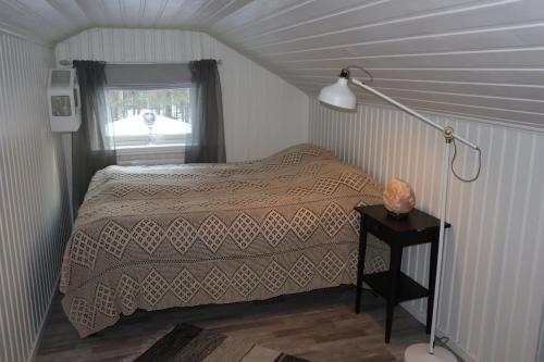 een slaapkamer met een bed en een lamp op een tafel bij Lekvattnet 123 in Torsby