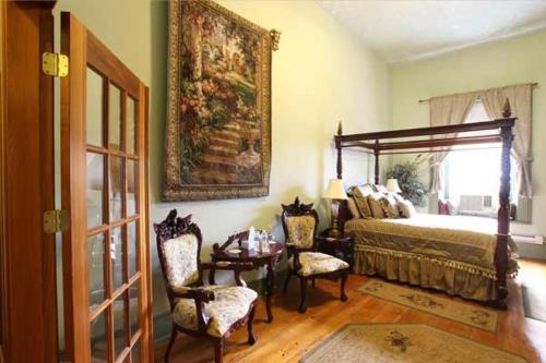 a bedroom with a bed and a table and chairs at Baldachin Inn in Merrickville