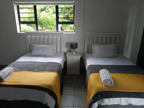 two beds in a room with two windows at Bee Comfy in Klein Brak Rivier