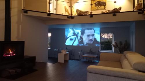 a living room with a couch and a big screen tv at La Maison du Lac in Flavignac
